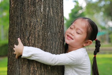 Gülümseyen çocuk kız kucaklayan ağaç Garden'da kapalı gözlerle.