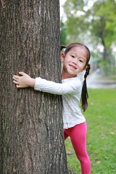 Uśmiechnięte Dziecko Dziewczynka Ogarnięcie Drzewa Oczy Zamknięte Ogrodzie — Zdjęcie stockowe