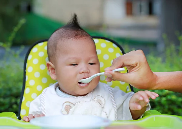 关闭婴儿婴儿的男孩在花园的椅子上喂养食物 婴儿第一次喂养食物 — 图库照片