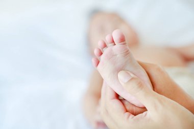 Yatakta onun bebek bebek için anne yapma ayak masajı.