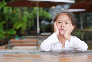 Şık ahşap masanın üzerinde yatan küçük Asyalı çocuk kız sen.