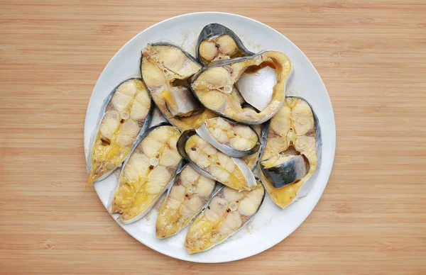 Steamed sliced striped catfish with on white plate against wooden board background.