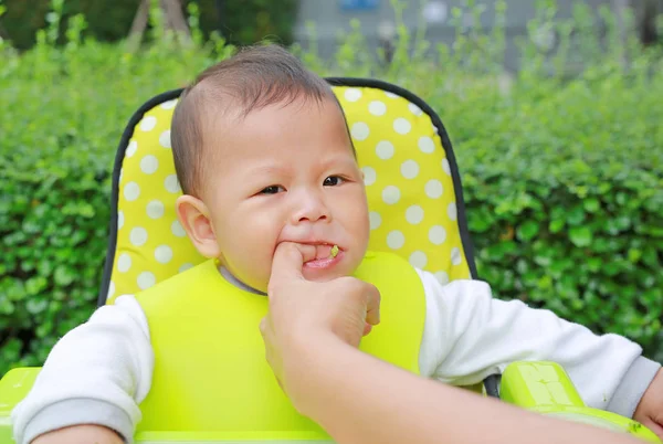 特写镜头的男婴坐在孩子的椅子上吃饭 嘴里塞着什么东西 母亲帮助远离 — 图库照片