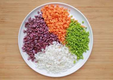 Ahşap arka plan beyaz tabakta kuşkonmaz, havuç, turp ve tatlı mor patates kıyılmış.