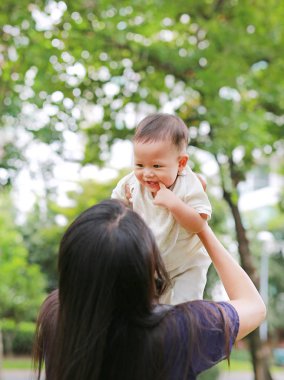 Asya Anne onun bebek Garden kollarında yukarı atar.