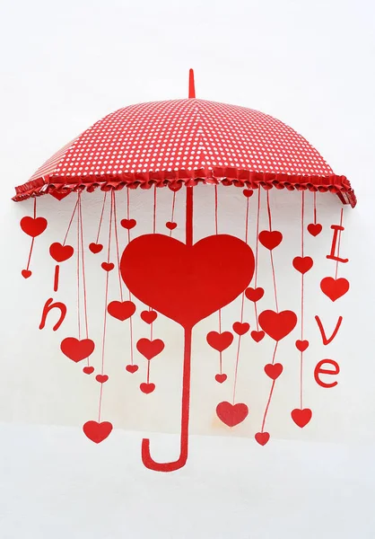 Creative decoration red umbrella with paint word ''In love'' place on the white cement wall.