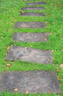 Parkta yeşil çimlerle kaplı taş patika..