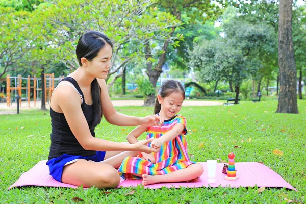 Mother appying body lotion for daughter\'s in the summer park.