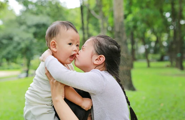 Fechar Bebê Menino Montando Ombro Mãe Com Irmã Beijando Parque — Fotografia de Stock