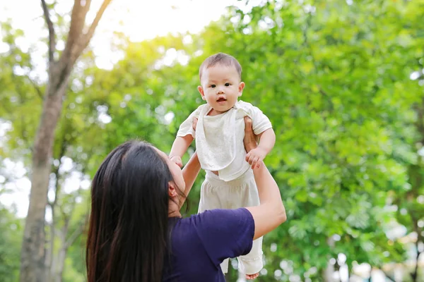 Asya Anne onun bebek bebek çocuk yaz bahçesi sabah güneş ışığı ile silah atar.