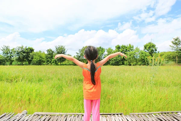 アジア子供少女の後姿は腕を伸ばすし 若い緑の水田でリラックス — ストック写真