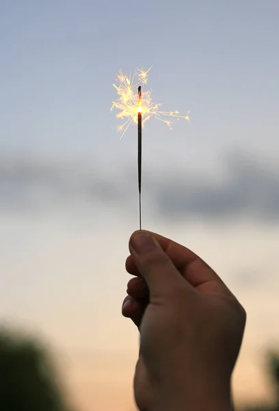 人の手の背景が祭で暗い火花火で遊んでいます — ストック写真