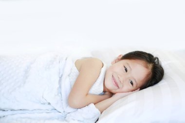 Yatakta yatarken mutlu uyuyan güzel Asyalı kız çocuk.