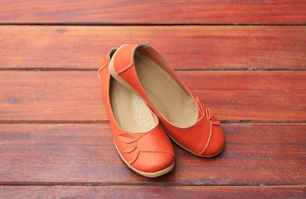 stock image Orange leather female shoes on wood