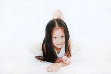 Şirin Asyalı kız yatak beyaz arka plan karşı yatan gülümseyen.