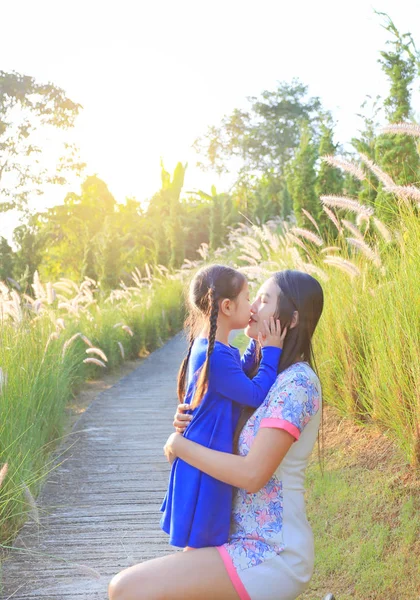 快乐的亚洲母亲和女儿亲吻在草地上的早晨 — 图库照片