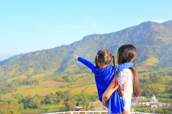 Visão Traseira Mãe Asiática Carregando Filha Varanda Encosta Apontando Que — Fotografia de Stock