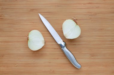 Taze soğan yarım keskin bıçak ile ahşap tahta arka plan üzerinde kesmek.