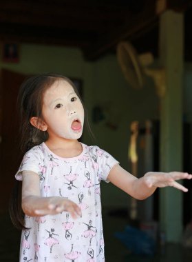 Küçük Asyalı çocuk kız oyun CE ile uygulamak yüzünü Talk pudrası ile.