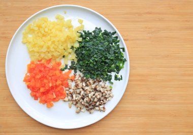 Ahşap tahta arka plan kopya alanı ile beyaz tabakta doğranmış sebze.