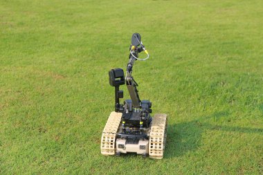 Bomb detection and disposal robot on green grass field. clipart