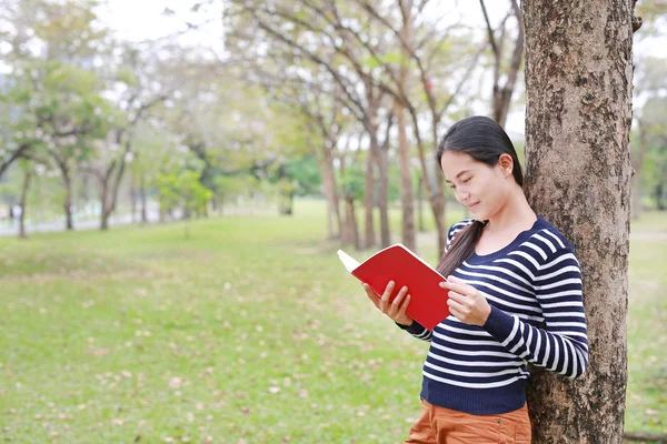 Mujer Joven Leyendo Libro Pie Apoyado Contra Árbol Del Tronco —  Fotos de Stock