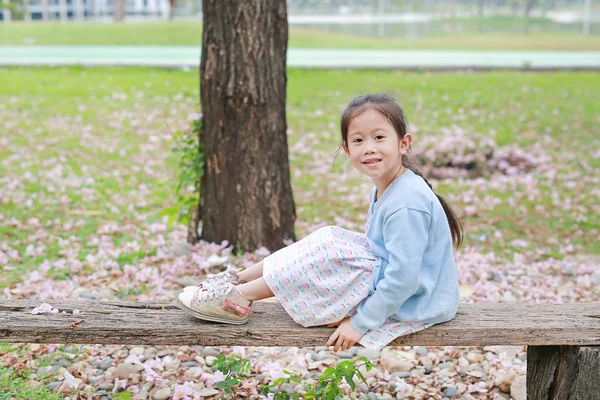 Sonriente Niña Sentada Troncos Madera Contra Caída Flor Rosa Jardín —  Fotos de Stock