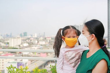 Bangkok şehir koruma maske Pm 2.5 hava kirliliğine karşı ile kızı taşıyan Asya anne. Tayland.