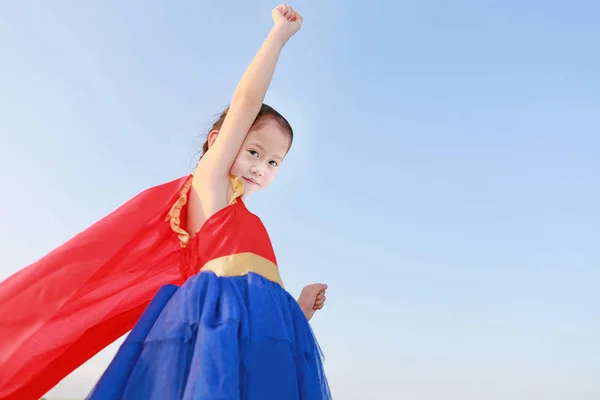 Małe dziecko dziewczyna superhero w gest latać na jasnym niebieskim sk — Zdjęcie stockowe