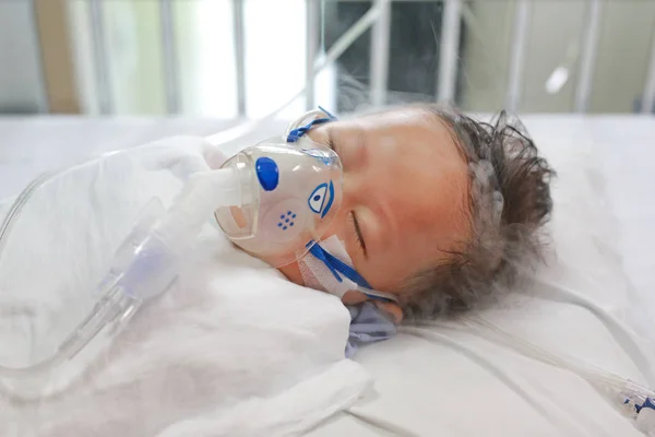 Hasta bebek hasta yatağında Solunum Syncytial Virüs (Rsv) tedavisi için teneffüs maskesi ile inhale ilaç uygulayarak.