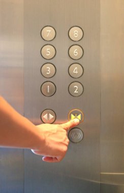 Asansördeki kapanış düğmesine basan işaret parmağı