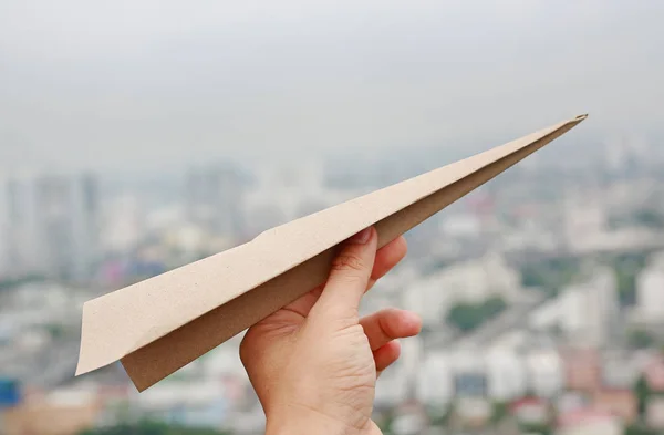 Brown aircraft rocket paper in hand fold to success on blur background of urban, Concept for business and travel plant.