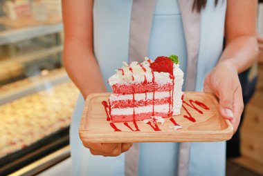 Kadın elleri kafede çilekli kek tutuyor..