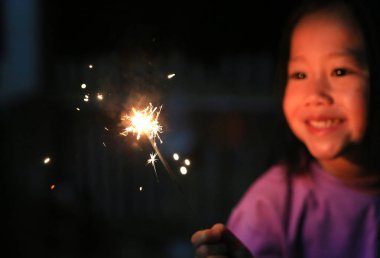 Küçük Asyalı çocuk kız havai fişek oynarken zevk.