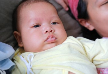 Asyalı bebeğin yakın yüzü tükürük oynuyor.