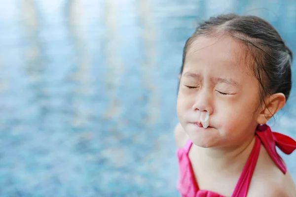 Mucus flowing from nose of little asian child girl while swimming at pool.