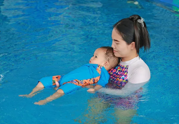 Young Asian mom teaching baby boy in swimming pool