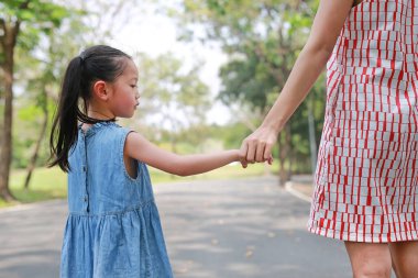 Yakın çekim anne ve kızı açık doğa bahçesinde el ele tutuşuyor. Geri görünüm.