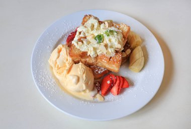 Beyaz tabak içinde meyve muz ve çilek ve dondurma ile servis bal tost.