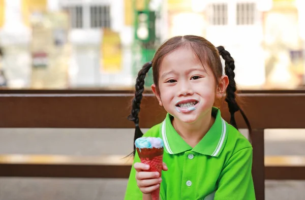 快乐的小亚洲孩子女孩喜欢吃冰淇淋锥与染色周围她的嘴 — 图库照片