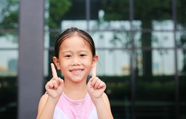 亚洲小女孩的姿势指着她的食指 带着小小的微笑 — 图库照片
