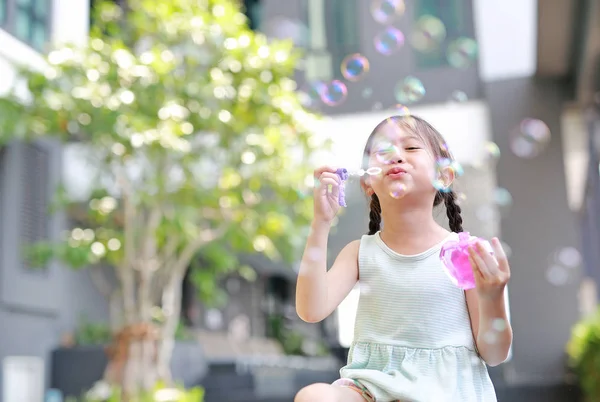 Счастливая маленькая девочка играет мыльные пузыри в саду . — стоковое фото