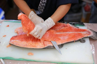 Japon Şef somon suşi için çiğ balık dilimleme. Bir kesme tahtası üzerinde taze somon hazırlama Şef.