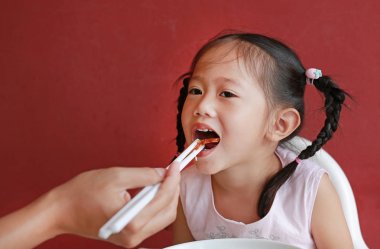Anne kızı sandalyesi kırmızı duvar arka plan üzerinde için şehriye besleme.