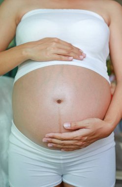 Karnı üzerinde ellerini tutan hamile kadın.