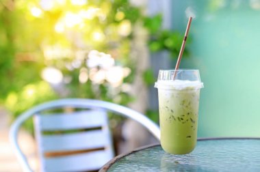 Doğa bahçe arka plan karşı masa ve sandalye üzerinde süt ile buzlu yeşil çay matcha latte.