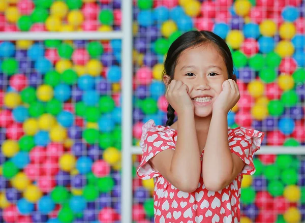 Menina Asiática Pequena Feliz Mantém Ambas Mãos Bochechas Contra Playground — Fotografia de Stock