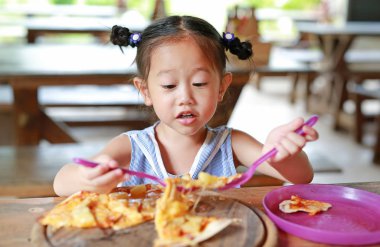 Küçük kız çocuk zevk pizza masada yemek.