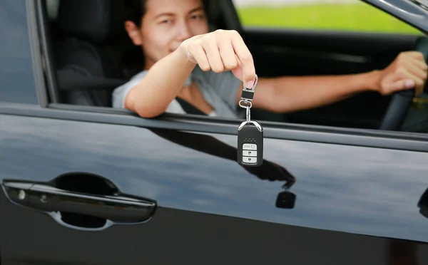 年轻的亚洲女人在车里 把钥匙从窗户拿出来 集中在她手上挂着的钥匙 — 图库照片
