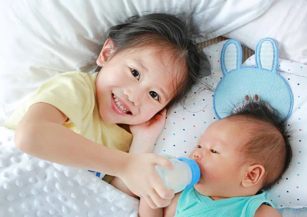 Feliz Hermana Alimentando Leche Biberón Para Hermano Acostada Cama —  Fotos de Stock